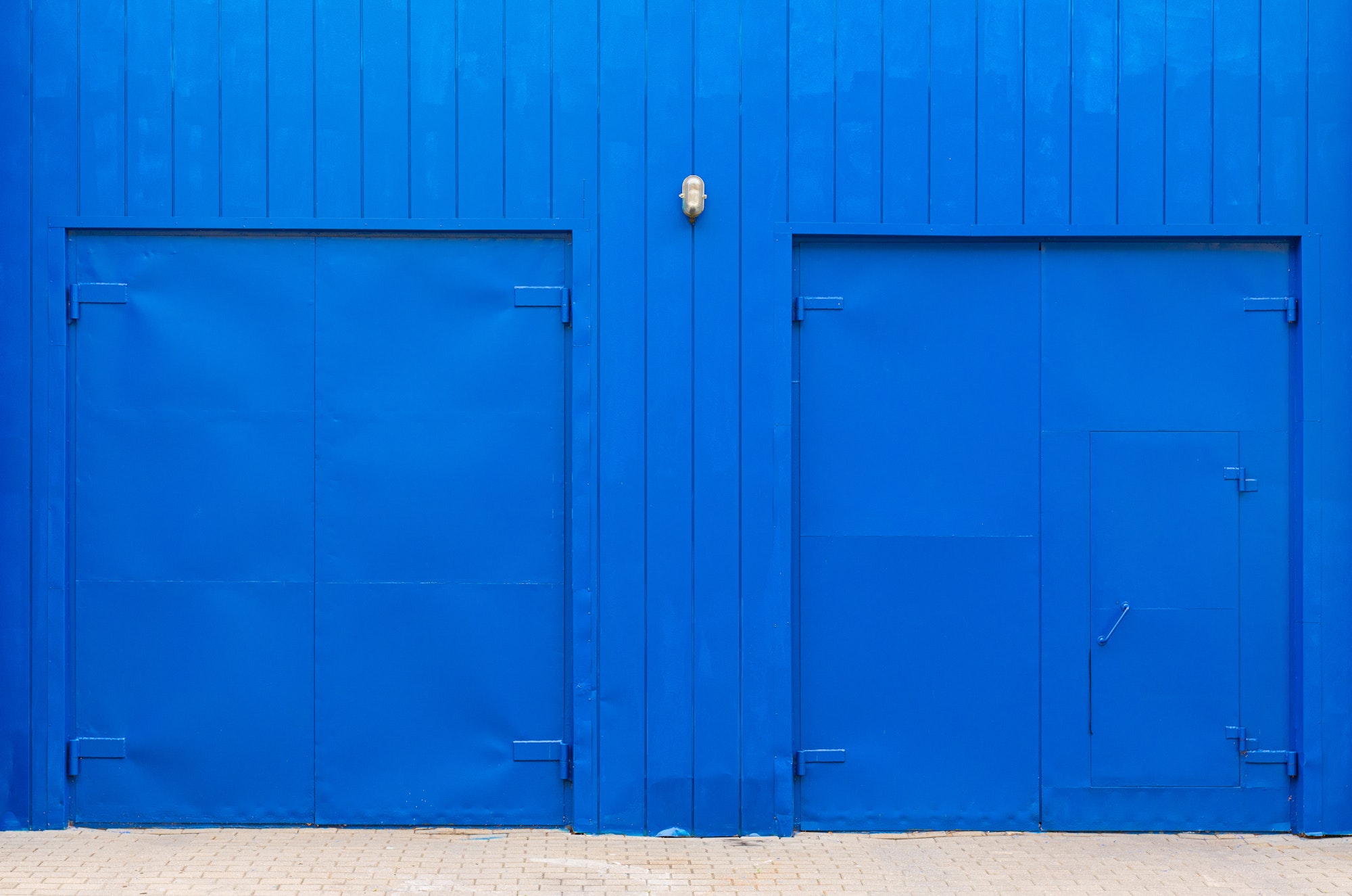 Electric blue wall woth wooden planks and wide blue doors.